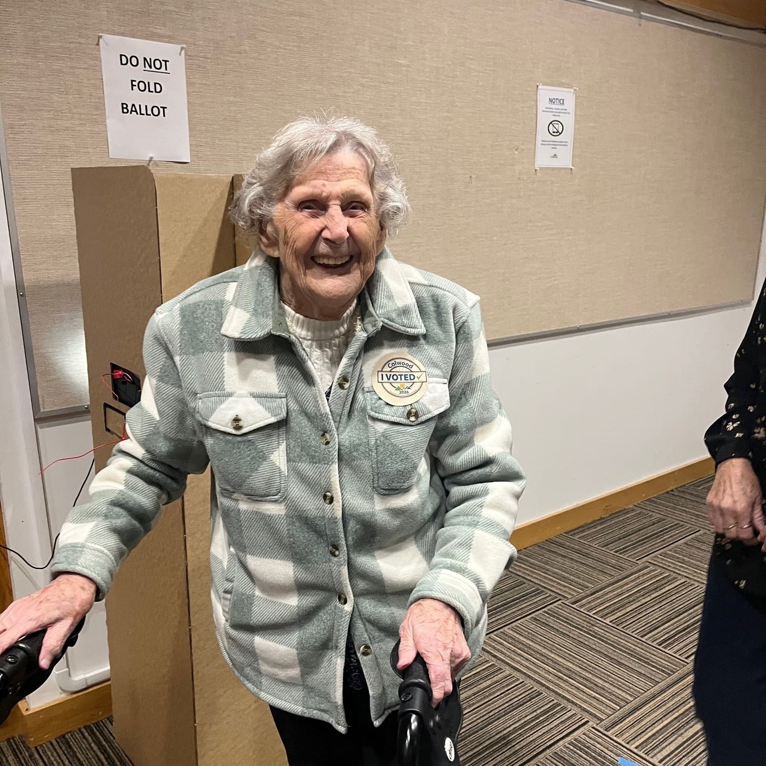 Issue image: A Colwood voter wearing an I Voted sticker, smiling with a walker at the polling place.